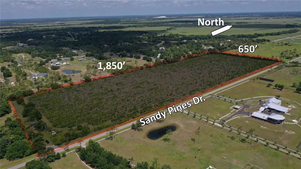 An aerial view shows a large, rectangular plot of land outlined in red near a road — 2121 SANDY PINE DRIVE, PUNTA GORDA, FL
