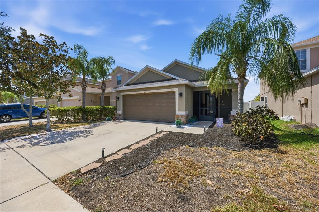 A single-story suburban house with a two-car garage, a screened entryway, and palm trees — 1111 SEMINOLE SKY DRIVE, RUSKIN, FL