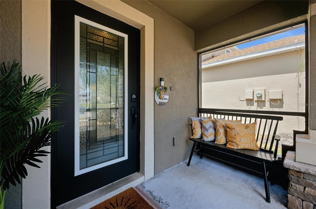 A covered front porch features a black door with glass panels and a black bench — 1111 SEMINOLE SKY DRIVE, RUSKIN, FL