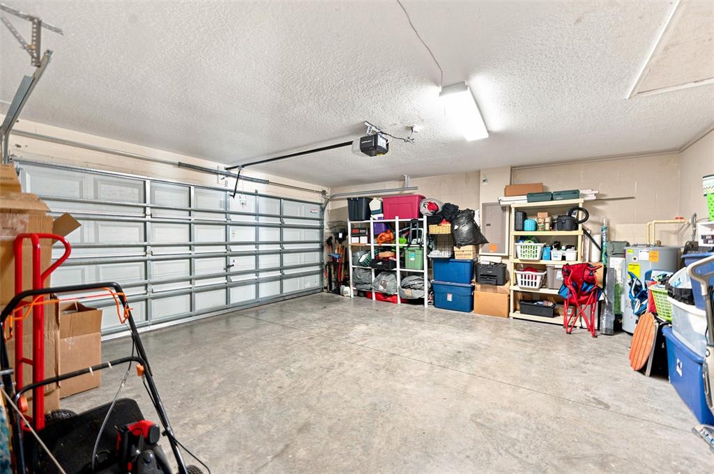 A garage with a concrete floor, storage shelving, and a white sectional garage door — 1111 SEMINOLE SKY DRIVE, RUSKIN, FL
