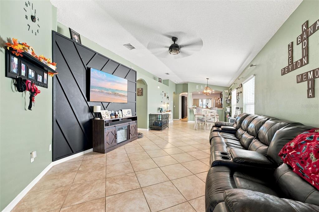 A living room features a black accent wall with a television, tile flooring, and a sofa — 1111 SEMINOLE SKY DRIVE, RUSKIN, FL