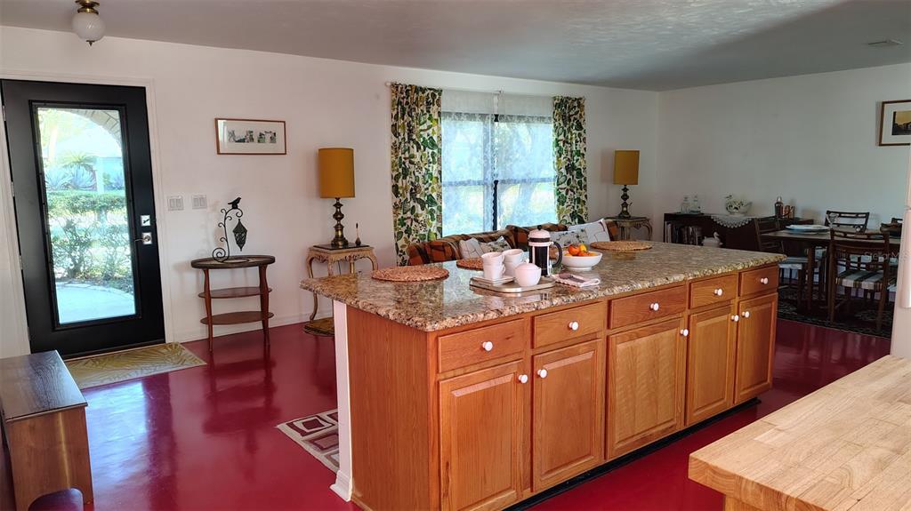 A kitchen island with granite countertops sits in a room with red flooring — 4790 MICHAEL LANE, PONCE INLET, FL
