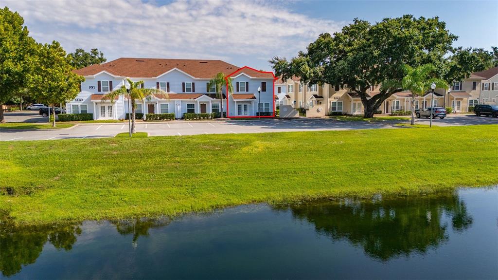 An exterior view of a multi-story townhouse building situated next to a pond — 5370 DIPLOMAT COURT UNIT 108, KISSIMMEE, FL