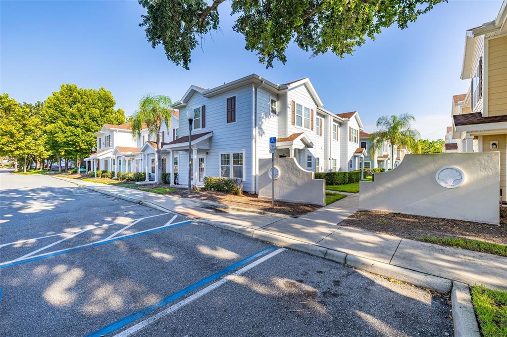 A row of light blue two-story townhomes sits beside a parking lot with a sidewalk — 5370 DIPLOMAT COURT UNIT 108, KISSIMMEE, FL