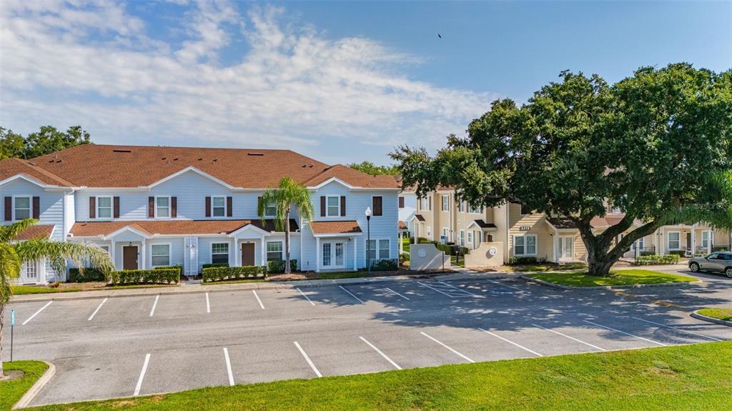 A multi-unit residential building with light blue siding stands behind a paved parking lot — 5370 DIPLOMAT COURT UNIT 108, KISSIMMEE, FL