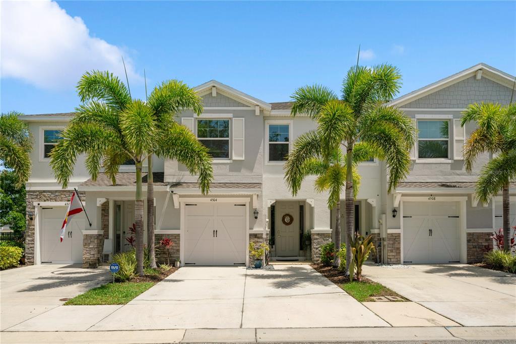 A row of three two-story townhomes with white garage doors and palm trees in front — 4504 SILVER LINING STREET, SARASOTA, FL