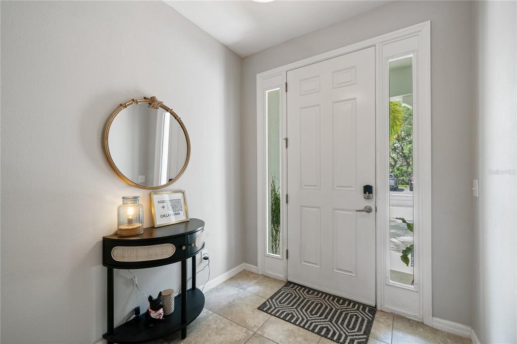 A bright entryway features a white front door, tiled floors, and a black console table — 4504 SILVER LINING STREET, SARASOTA, FL