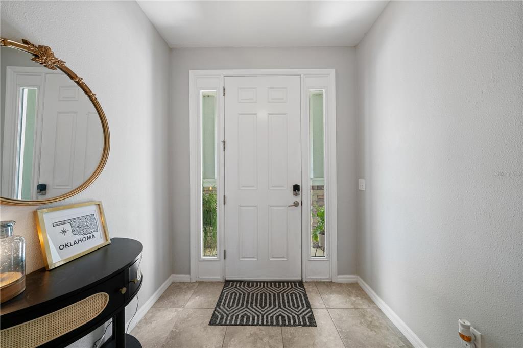 A bright entryway features a white front door with sidelights, tile flooring, and a console table — 4504 SILVER LINING STREET, SARASOTA, FL
