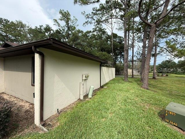 A side view of a house exterior features a beige wall, brown trim, and utility equipment — 1605 NE 38TH TERRACE, OCALA, FL