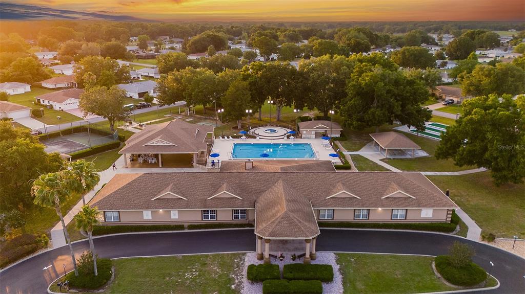 An aerial view of a community clubhouse featuring a swimming pool, tennis court, and parking — 6093 SW 96TH PLACE, OCALA, FL