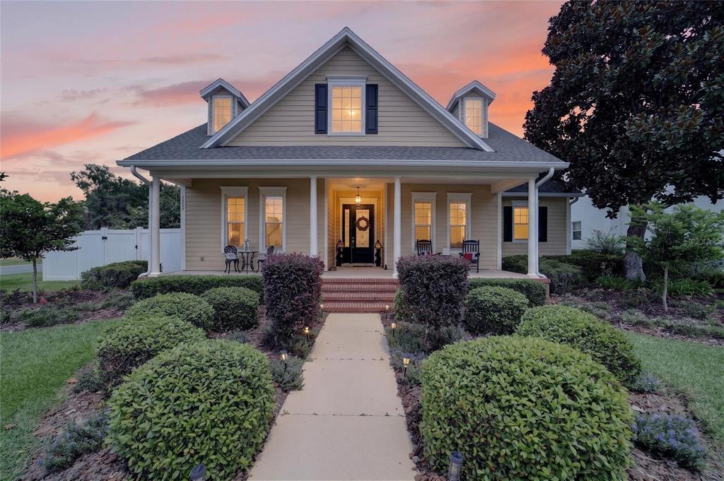 A tan house with a front porch, dormer windows, and a landscaped walkway at sunset — 4713 SE 28TH STREET, OCALA, FL