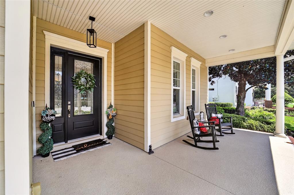 A covered front porch features a black door, two rocking chairs, and light-colored siding — 4713 SE 28TH STREET, OCALA, FL