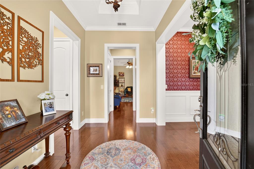 An entryway features hardwood floors, a round rug, a console table, and a red-wallpapered room — 4713 SE 28TH STREET, OCALA, FL