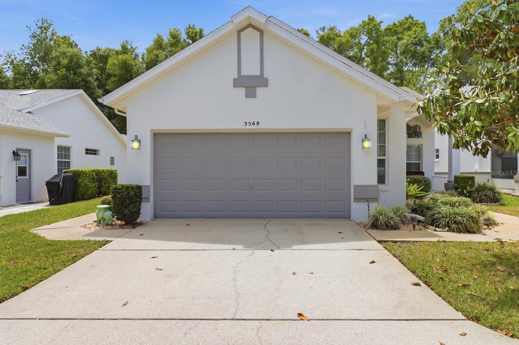 A white house with a gray two-car garage and a concrete driveway — 3569 S BELGRAVE DRIVE, INVERNESS, FL