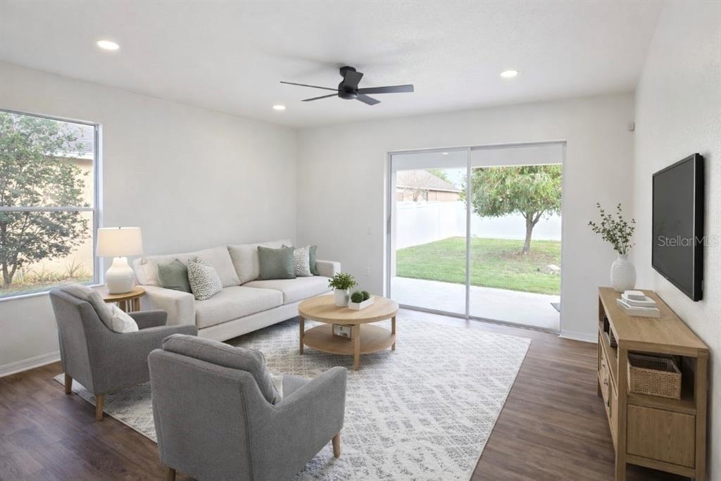 A living room features a sofa, two armchairs, a coffee table, and a sliding glass door — 1911 WIND MEADOWS DRIVE, BARTOW, FL