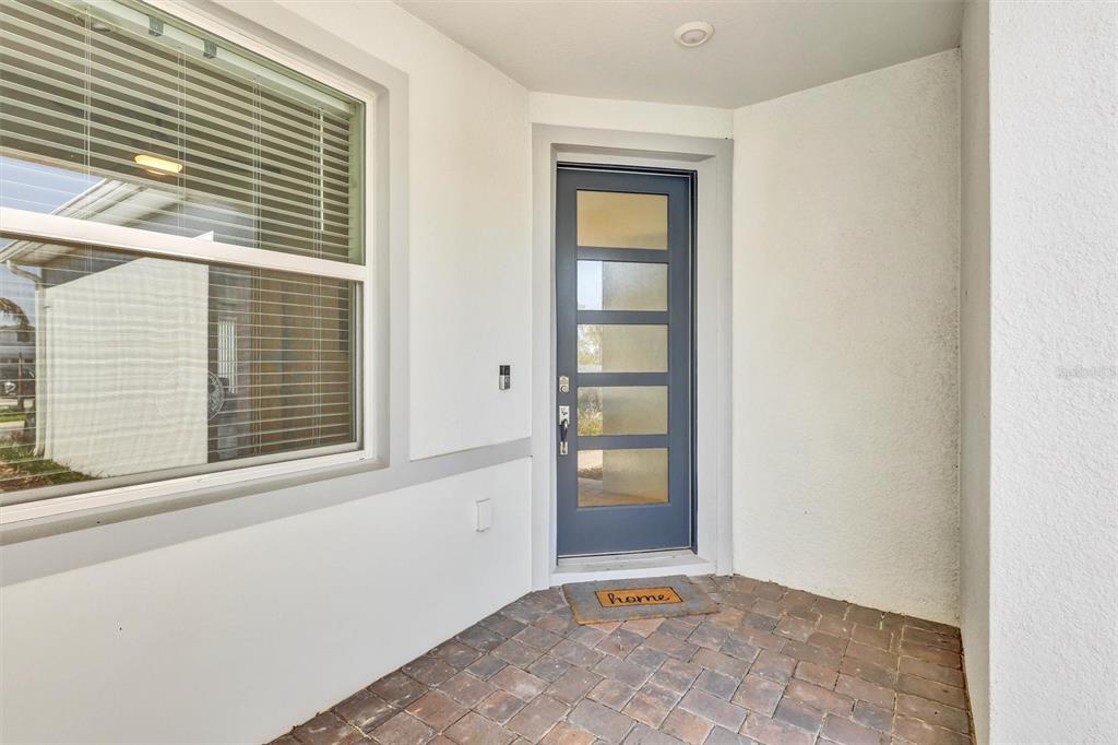 A blue front door with five horizontal glass panels sits on a brick porch — 15806 GEM VIEW ST, WINTER GARDEN, FL