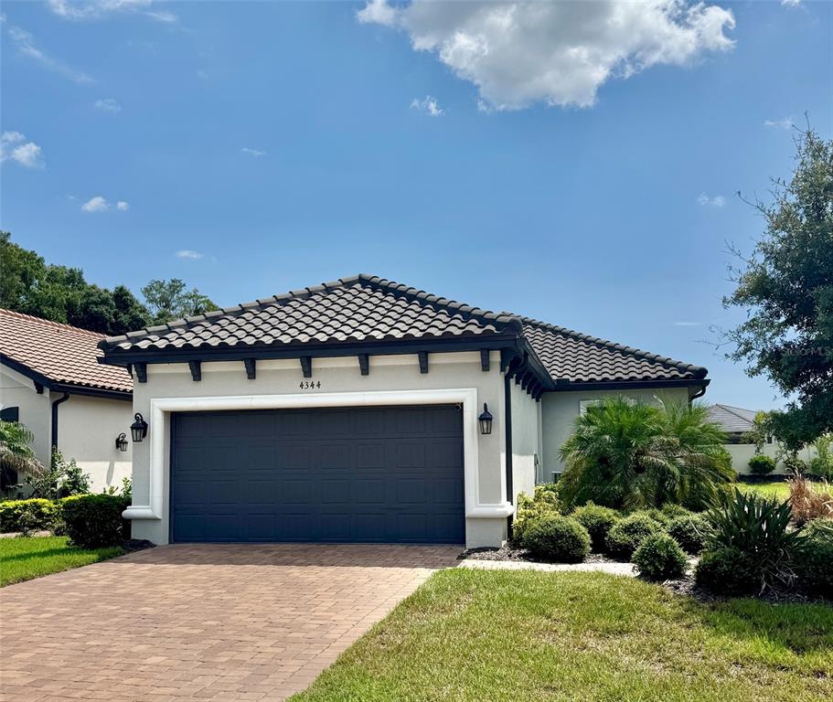 A single-story house with a dark tiled roof, a gray garage door, and landscaped front yard — 4344 CAIROLI COURT, WESLEY CHAPEL, FL