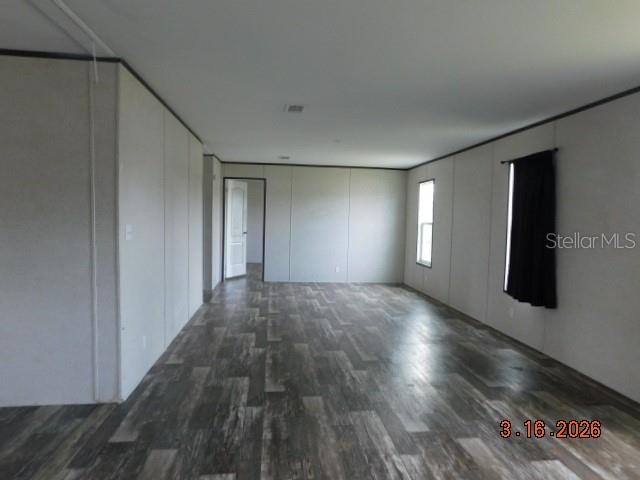 An empty room features light-colored walls, dark wood-look flooring, and a window with curtains — 8236 SWEDEN BOULEVARD, PUNTA GORDA, FL
