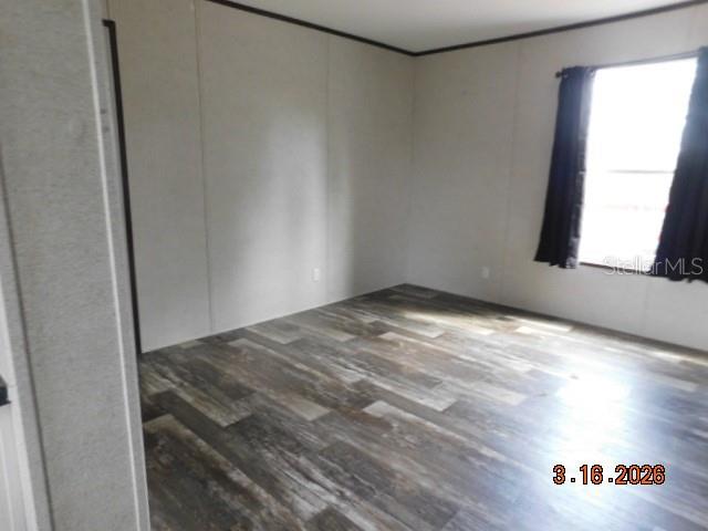 An empty room features light-colored walls, dark wood-look flooring, and a window with curtains — 8236 SWEDEN BOULEVARD, PUNTA GORDA, FL