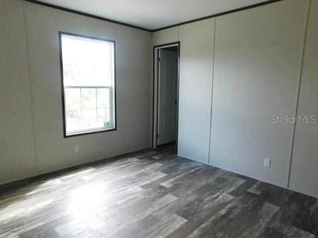 An empty bedroom features light-colored walls, a window, and wood-look flooring — 8236 SWEDEN BOULEVARD, PUNTA GORDA, FL