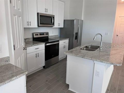 A kitchen features white cabinets, stainless steel appliances, granite countertops, and a center island — 4716 HOMESTEAD TRAIL, ST CLOUD, FL