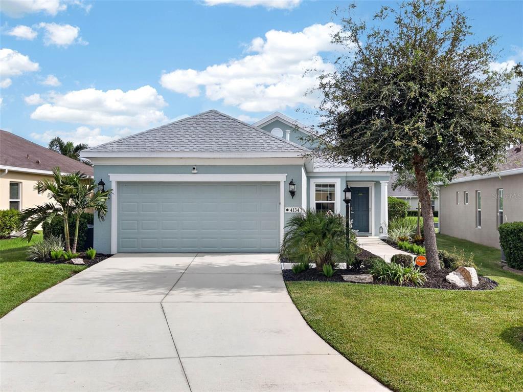 A light blue single-story house with a two-car garage and a paved driveway — 4134 DEEP CREEK TERRACE, PARRISH, FL