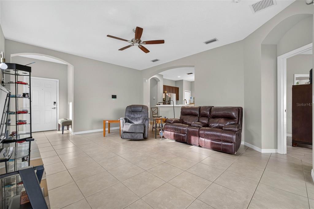 A living room with tile flooring, a ceiling fan, and a brown leather loveseat — 4134 DEEP CREEK TERRACE, PARRISH, FL