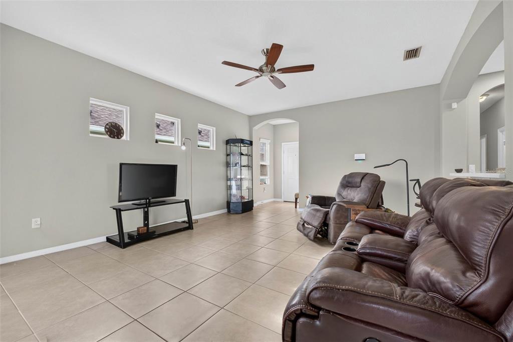 A living room with tile flooring, a ceiling fan, a television, and leather furniture — 4134 DEEP CREEK TERRACE, PARRISH, FL