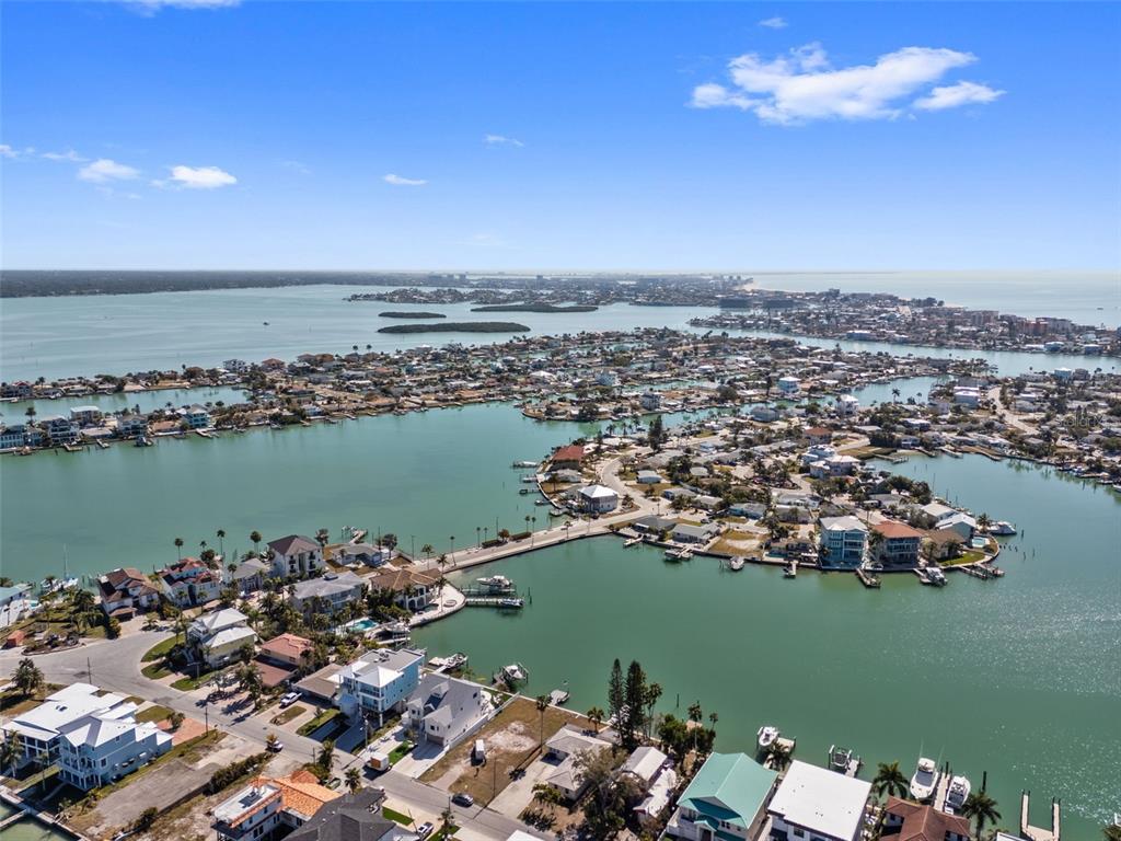 An aerial view shows a coastal neighborhood with houses, canals, and a bridge — 837 BAY POINT DRIVE, MADEIRA BEACH, FL