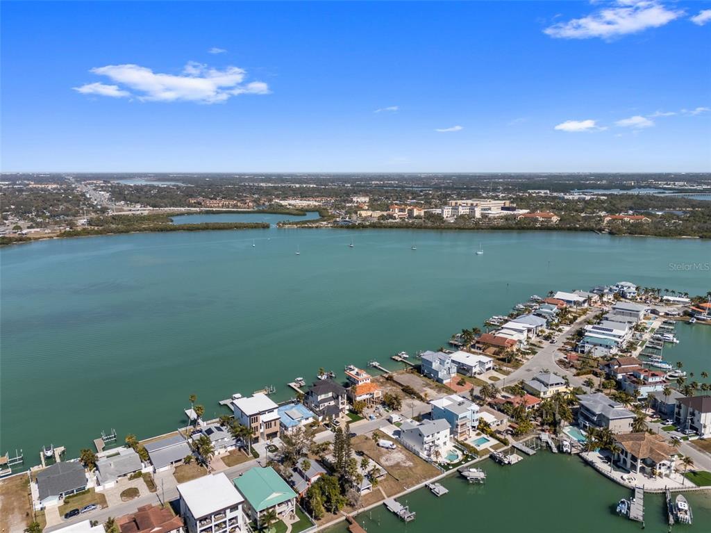 An aerial view shows waterfront houses with private docks along a bay under a blue sky — 837 BAY POINT DRIVE, MADEIRA BEACH, FL