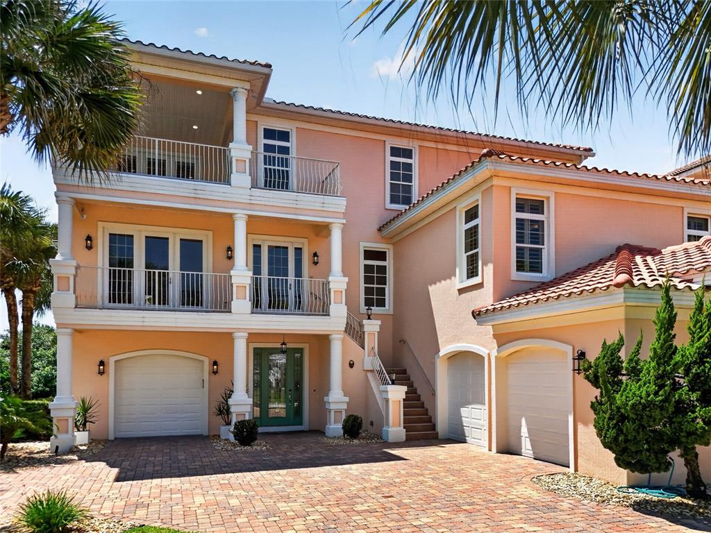 A three-story peach-colored house with a brick driveway, multiple balconies, and three garage doors — 1 OCEAN RIDGE BOULEVARD N, PALM COAST, FL