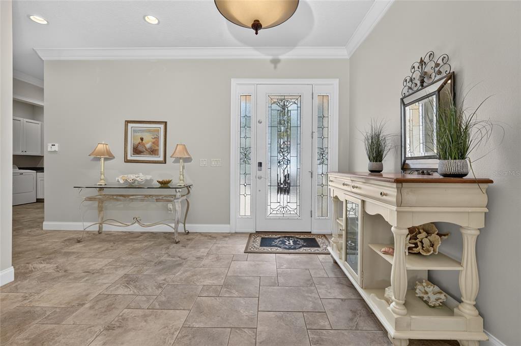 A tiled entryway features a glass-paneled front door, two console tables, and neutral wall paint — 1 OCEAN RIDGE BOULEVARD N, PALM COAST, FL