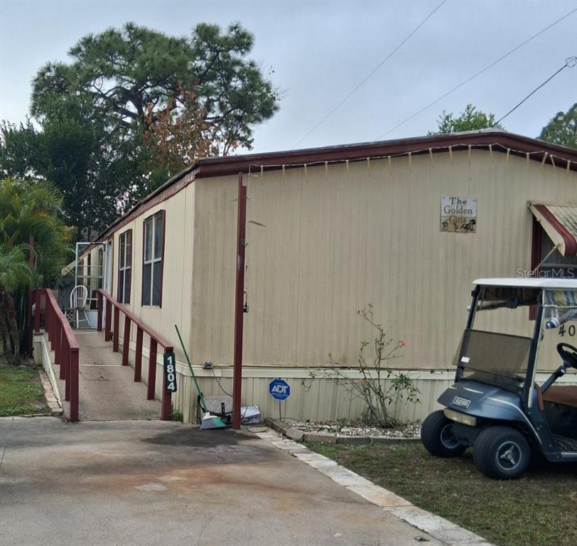 A beige mobile home features a wooden wheelchair ramp and a golf cart parked outside — 1804 DOROTHY BOULEVARD UNIT 403, LUTZ, FL