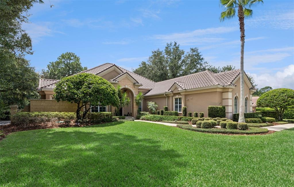 A single-story house with a beige stucco exterior, tile roof, and a manicured front lawn — 1738 BRACKENHURST PLACE, LAKE MARY, FL