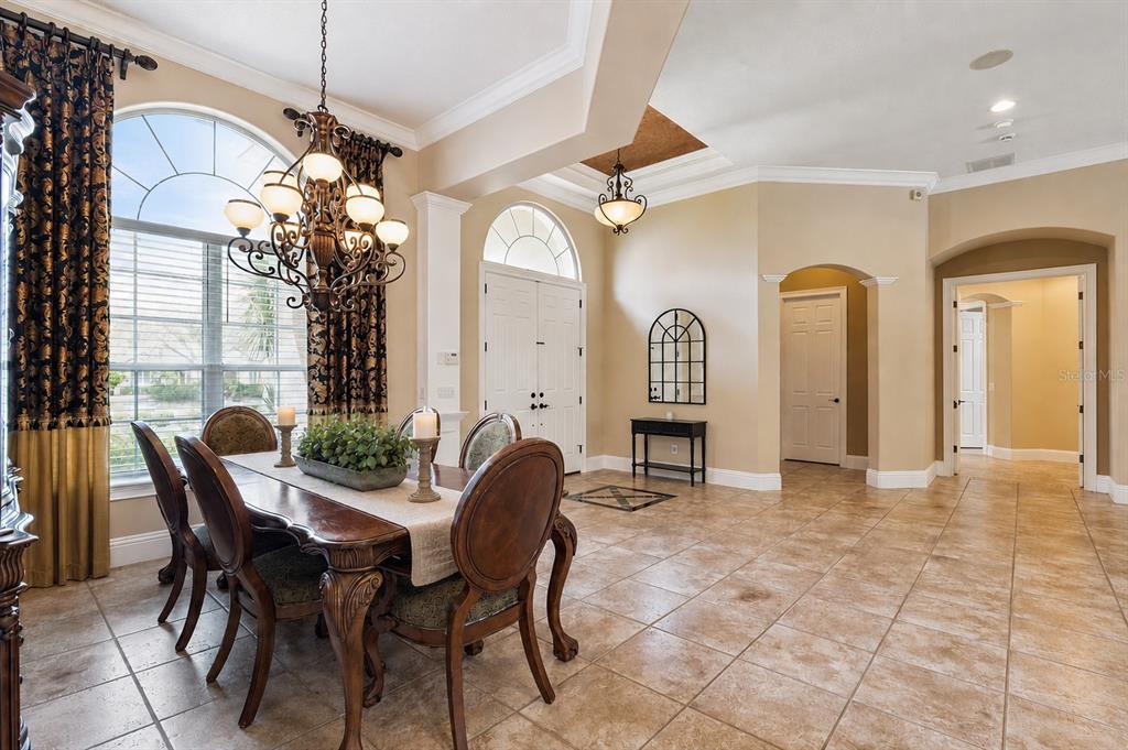 A dining room with tile floors, a wooden table, and a chandelier near an entryway — 1738 BRACKENHURST PLACE, LAKE MARY, FL