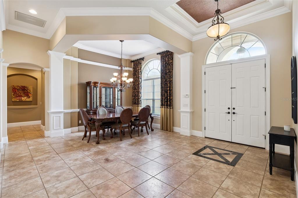 A dining area with tile floors and a chandelier sits adjacent to a white double-door entryway — 1738 BRACKENHURST PLACE, LAKE MARY, FL