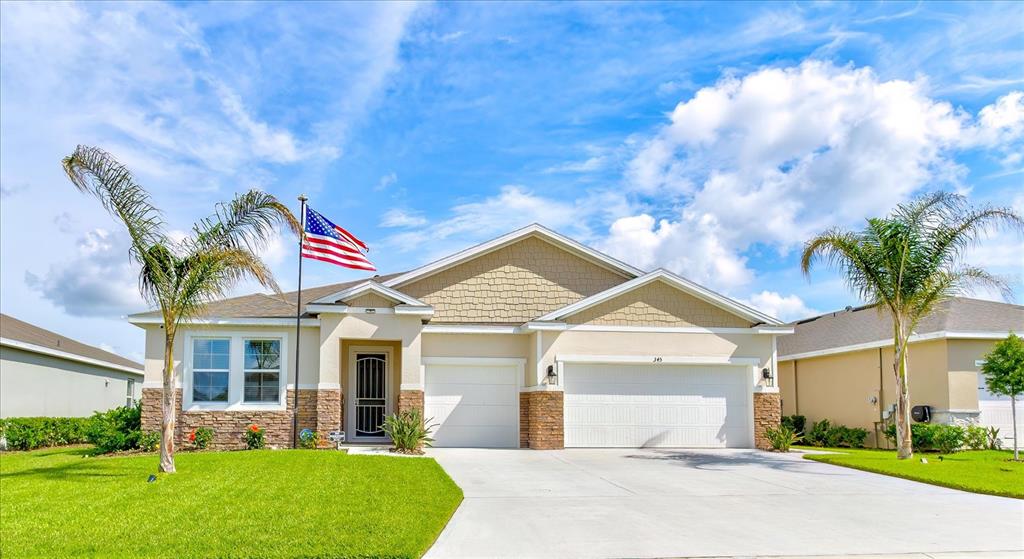 A single-story suburban house with a two-car garage, stone accents, and two palm trees — 345 E MERIMONT LANE, ORMOND BEACH, FL