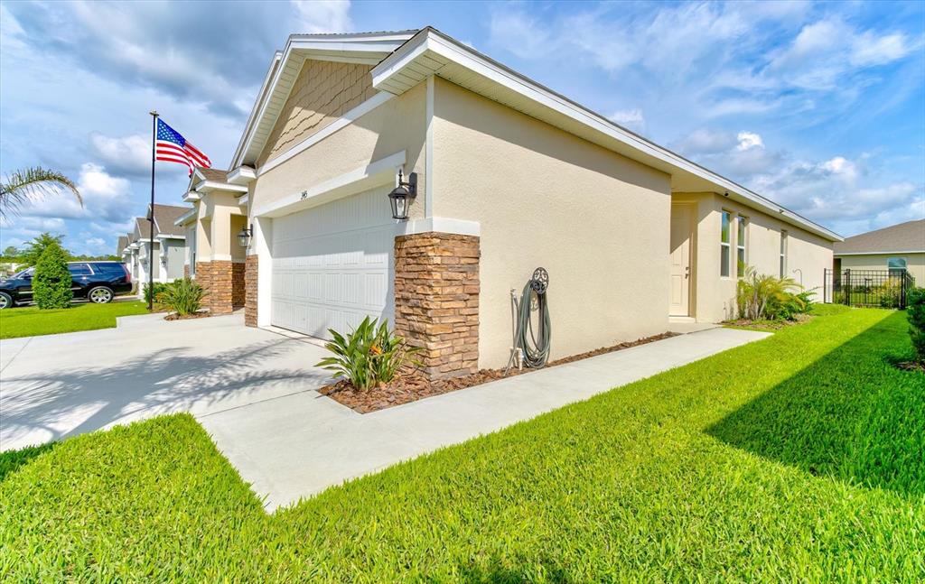 A single-story house with a white garage, stone accents, and a green lawn — 345 E MERIMONT LANE, ORMOND BEACH, FL