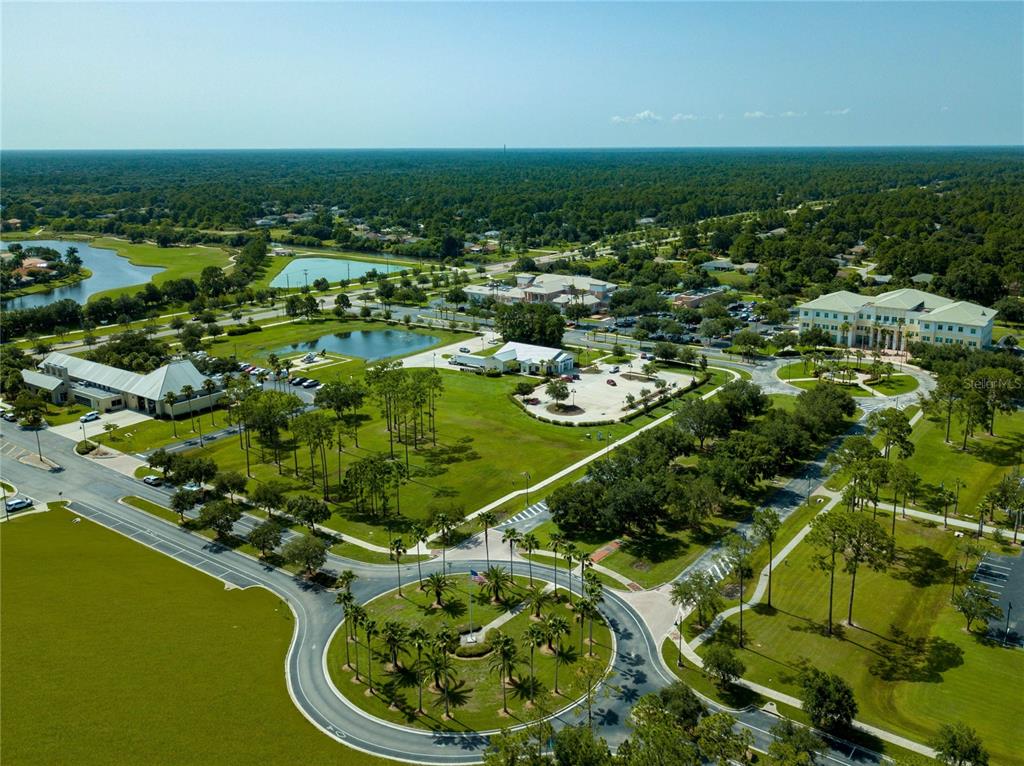 An aerial view shows a circular driveway, green lawns, ponds, and several commercial buildings — NOPPENBERG AVENUE, NORTH PORT, FL