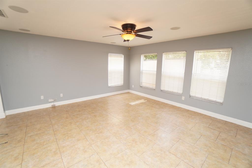 An empty room with light gray walls, tile flooring, and a ceiling fan — 113 RONA LANE, DAVENPORT, FL