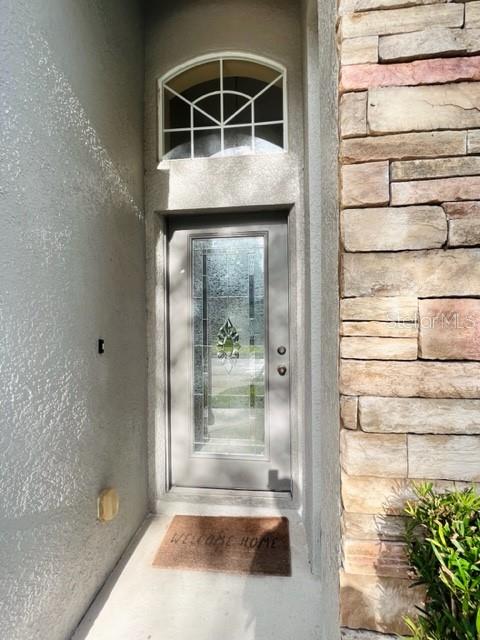 A front entryway features a glass-paneled door, an arched transom window, and stone exterior siding — 30 CHIPPENDALE TERRACE, OVIEDO, FL