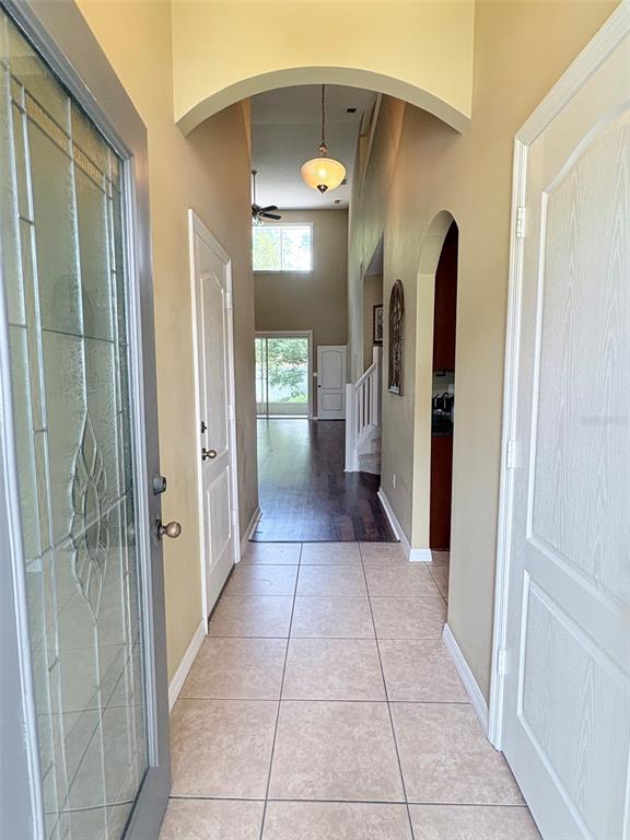An entryway with tile flooring leads to a hallway with wood floors and arched doorways — 30 CHIPPENDALE TERRACE, OVIEDO, FL