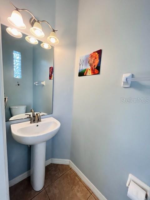 A powder room features a pedestal sink, a wall-mounted mirror, and a small landscape painting — 30 CHIPPENDALE TERRACE, OVIEDO, FL