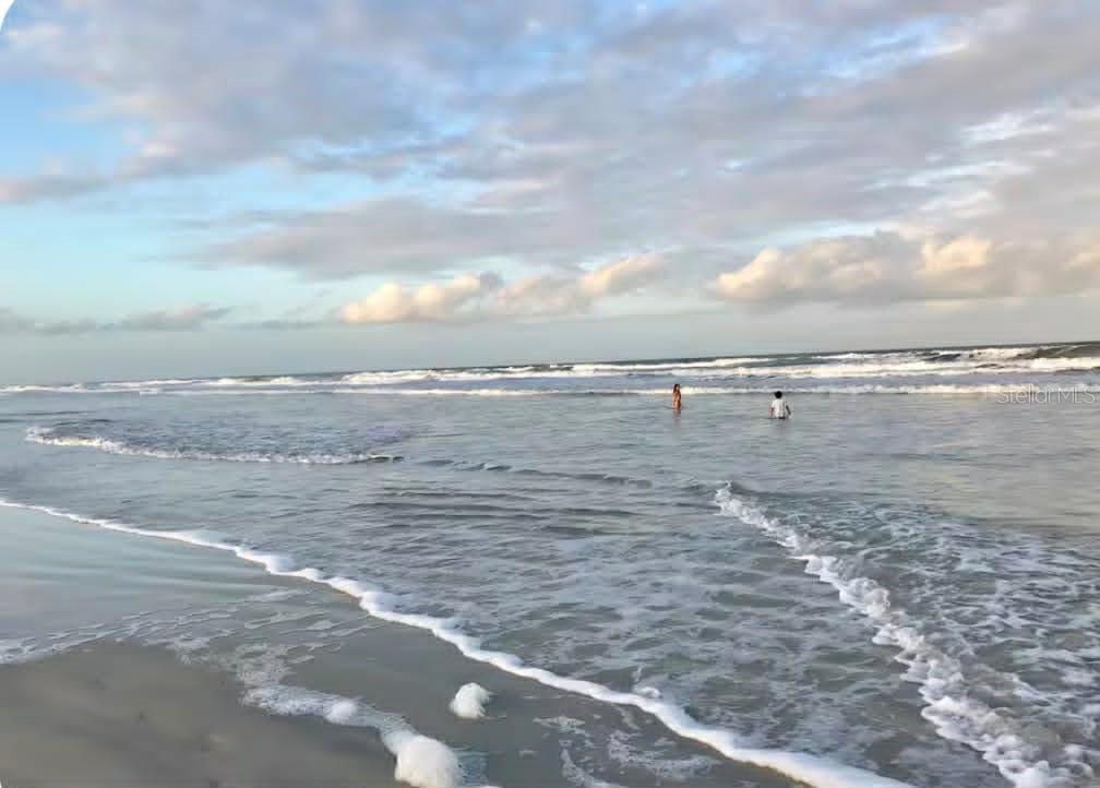 Two people stand in the shallow water of a beach under a cloudy sky — 6300 S A1A BOULEVARD UNIT A93U, ST AUGUSTINE, FL