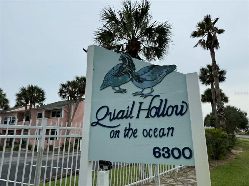 A sign for Quail Hollow on the ocean stands in front of a pink building — 6300 S A1A BOULEVARD UNIT A93U, ST AUGUSTINE, FL