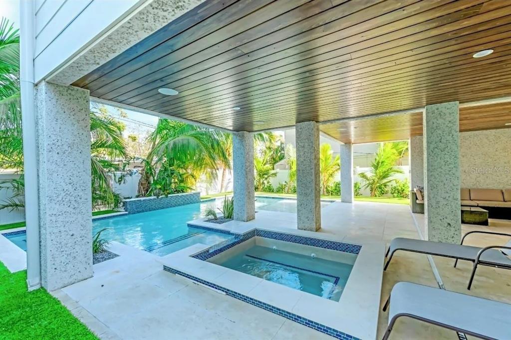 A covered patio features a swimming pool, a built-in spa, and lounge chairs — 2403 AVENUE C, BRADENTON BEACH, FL