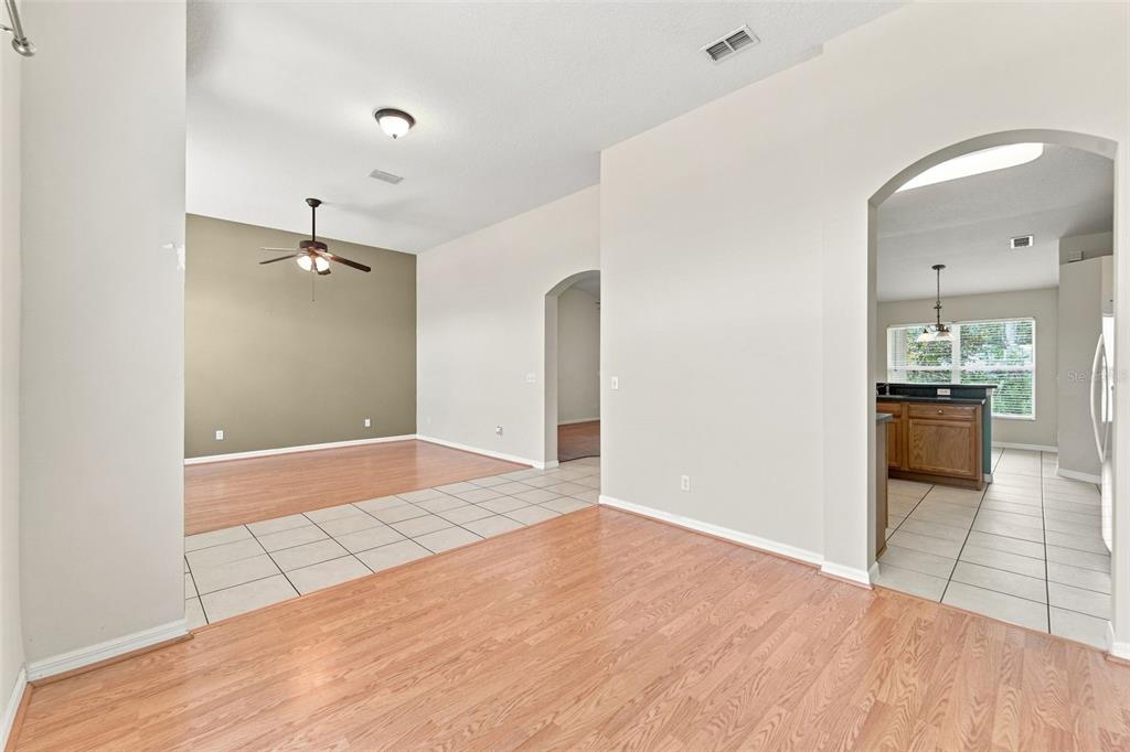 An interior view showing a living area with wood flooring and an adjacent tiled kitchen — 614 RED MULBERRY DRIVE, DELTONA, FL