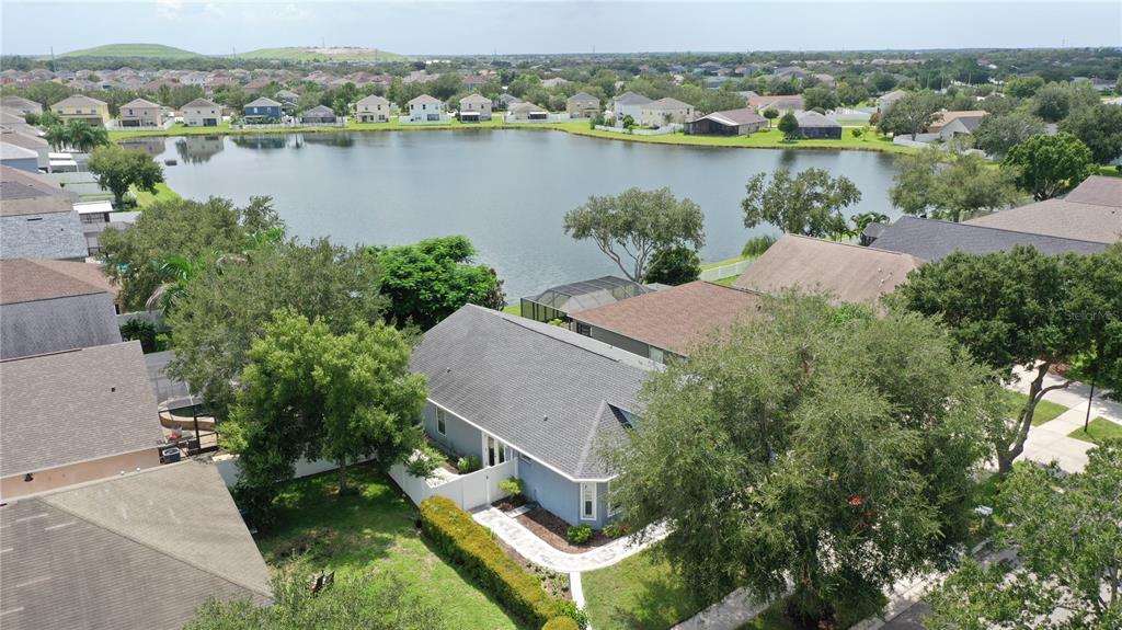 An aerial view shows a blue house with a gray roof overlooking a large lake — 13429 FLADGATE MARK DRIVE, RIVERVIEW, FL