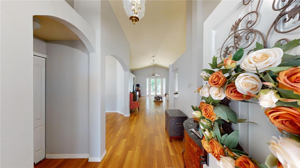 A view from an entryway looking down a hallway with wood floors and arched openings — 13429 FLADGATE MARK DRIVE, RIVERVIEW, FL