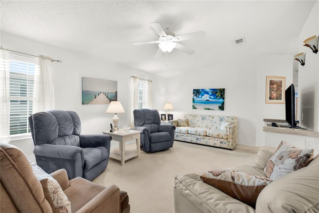 A living room featuring a ceiling fan, carpeted floors, and several pieces of upholstered furniture — 222 SUE AVENUE, DAVENPORT, FL